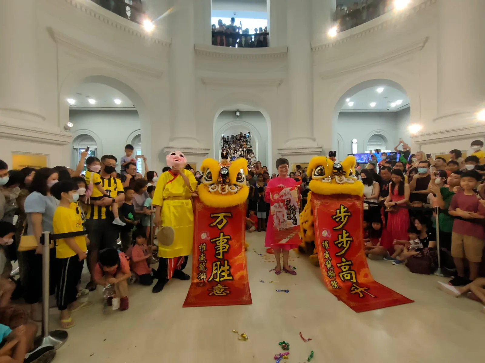 Lion dance performance with calligraphy scrolls at an indoor event in Singapore